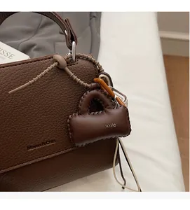 Detailed view of dark brown pebbled leather texture and mini bag charm on stylish tote