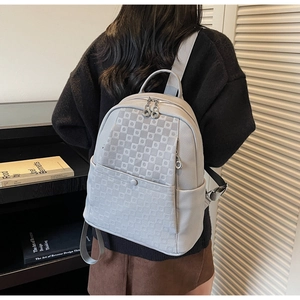 Rear view of a model wearing the grey geometric pattern backpack with leather texture