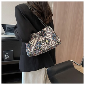 Detail of woven tote bag with colorful geometric patterns and black metal chain strap