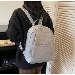 Detailed view of grey litchi texture backpack featuring embossed grid pattern on front pocket