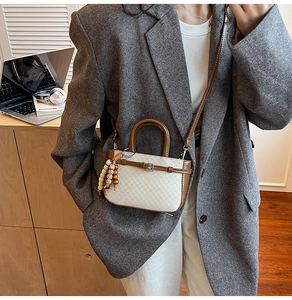Detail of checkered crossbody bag with brown leather trim and ethnic charm pendant