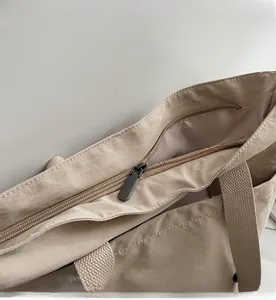 Détail de la fermeture éclair et de la doublure à logo du sac cabas beige épuré