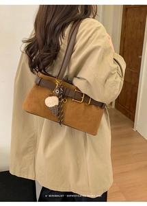 Close-up of retro baguette shoulder bag with plush pendant and suede texture