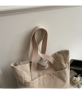 Détail du cabas en toile montrant des poignées larges et une grande poche frontale