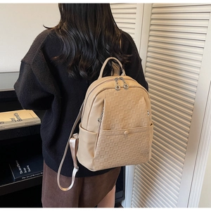Detail of light brown faux leather backpack with geometric texture on a model