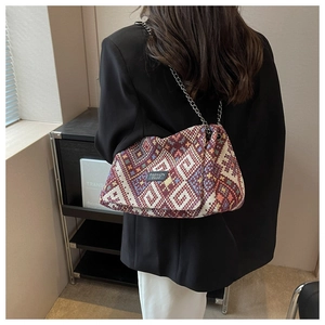 Close-up of geometric woven crossbody bag with silver chain strap on black blazer