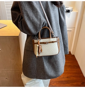 Detail showing the checkered cream texture and ethnic bead charm on a vintage handbag