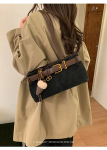 Detail of retro baguette bag with gold buckle and plush charm on a beige coat