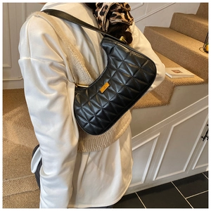Detail of black quilted crescent underarm bag with gold logo and diamond stitching
