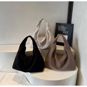 Trois sacs cabas en velours côtelé noir, beige et marron sur un socle minimaliste