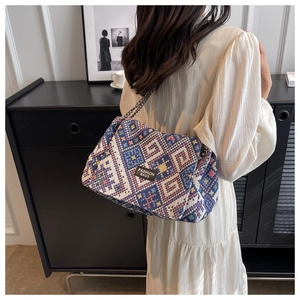Detail of bohemian geometric woven tote bag with metallic chain strap and fashion label