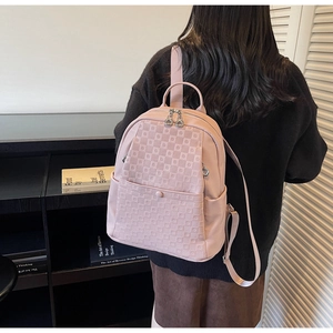 Pink pebbled leather backpack with diamond quilting and silver zipper shown on back
