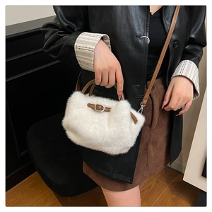 Detalle del bolso de felpa blanca con correas de cuero marrón y herrajes plateados