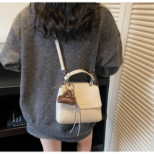 Detailed view of white litchi pattern leather square bag with small brown charm