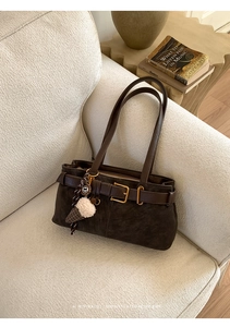 Detail of vintage dark brown baguette bag with suede texture and gold buckle hardware