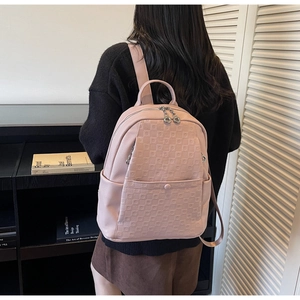 Pink lychee grain leather backpack with square embossed texture on a model in home setting