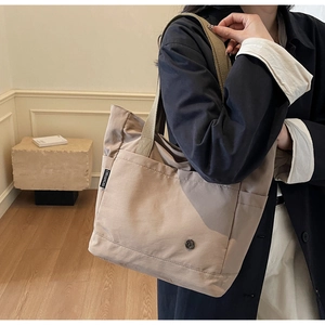 Détail du sac fourre-tout en toile kaki avec étiquette logo tissée et bouton métallique