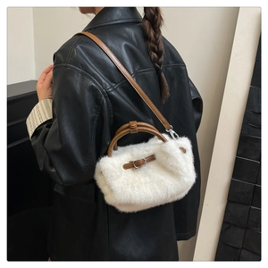 Detalle de bolso bandolera de felpa blanca con correas de cuero sobre una modelo