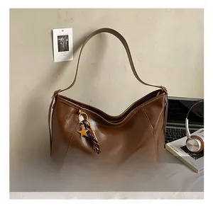 Détail du sac cabas marron foncé avec pendentif étoile et pompon tressé en cuir PU brillant