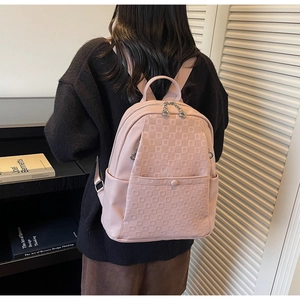 Detail of pink faux leather backpack with checkered embossing and front pocket