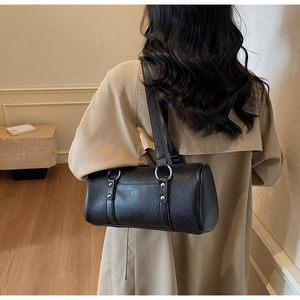 Detail of black cylindrical shoulder bag with silver ring hardware and rivet accents