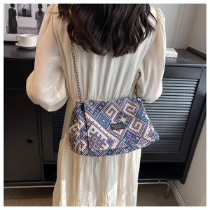 Detail of geometric pattern tote bag with chain strap and fashion label on woven fabric