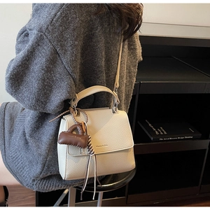 Detail view of cream lychee texture leather handbag with brand mini pouch attachment