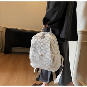 Detail of a beige leather backpack with checkerboard texture and silver zipper accents