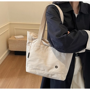 Gros plan détaillé du grand sac cabas en toile montrant sa texture et logo métal