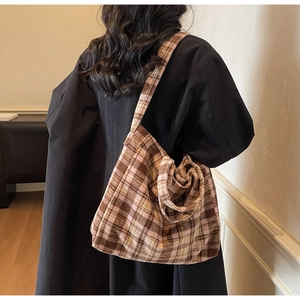 Détail du sac cabas à carreaux en laine porté sur un manteau d'hiver noir élégant