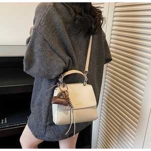Detail of creamy white textured leather bag with Maven & Chic logo and elegant tassel charm