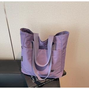 Détail du cabas en toile violette avec poches multiples et bandoulière large tissée