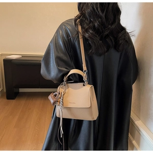Detailed back view of a beige leather shoulder bag with a heart-shaped brand charm