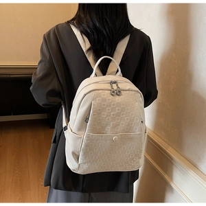 Chic cream-colored backpack with textured checkered pattern on minimalist interior background