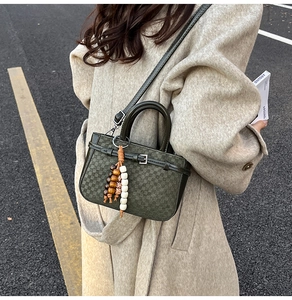 Detail of dark green checkered crossbody bag with unique wooden bead charm and handle