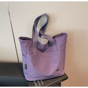 Vue détaillée du cabas en nylon violet avec poche frontale et étiquette tissée