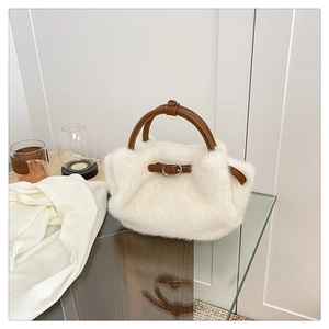 Detalle de bolso de peluche blanco con asa de cuero marrón y hebilla de metal