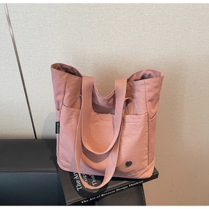 Détail du cabas en nylon rose montrant l'étiquette de la marque et la poignée tissée