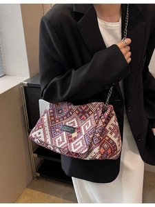 Ethnic geometric woven crossbody bag with metal chain strap shown on model shoulder