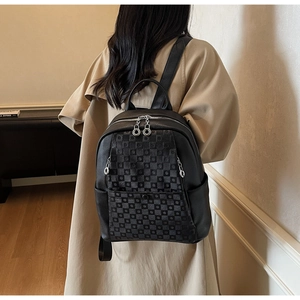 Detail of black checkered backpack with metal ring zipper being worn by a person