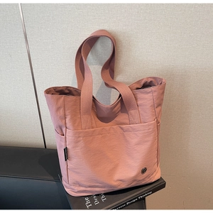 Détail du sac cabas en nylon rose Morandi avec poche avant et logo métallique