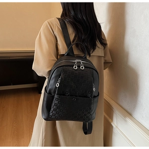 Rear view of a large black leather backpack with checkered detail on a female model