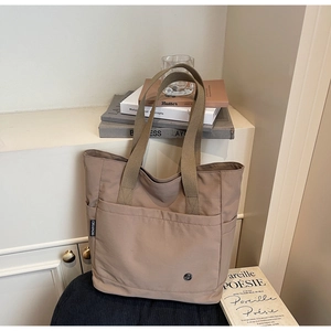 Détail du sac cabas en toile kaki avec poche frontale et poignées de transport tissées