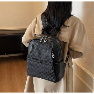 Detail of black pebbled leather backpack with checkered embossing and silver zippers