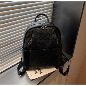 Close-up of black checkerboard textured backpack with metal zippers and side pocket detail