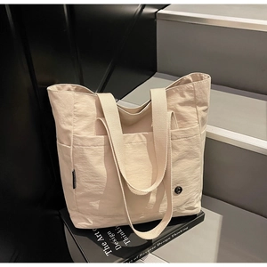 Détail d'un sac cabas en nylon beige clair avec finitions métalliques sur fond sobre
