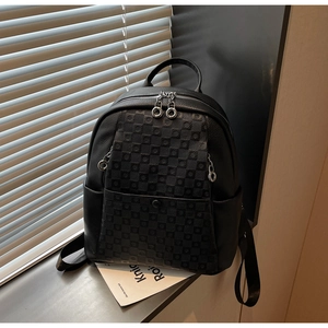 Detail of checkered pattern and lychee leather texture on a stylish black backpack