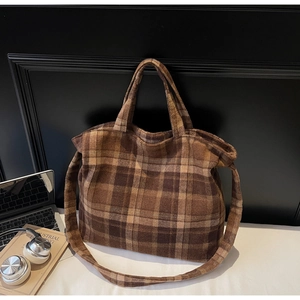 Close-up of brown plaid tote bag with laptop and books in a modern office setup