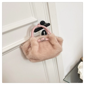 Detalle de bolso de peluche rosa con asa de cuero y hebilla metálica decorativa