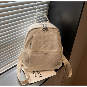 Detail of cream backpack featuring pebbled faux leather and checkered embossed texture
